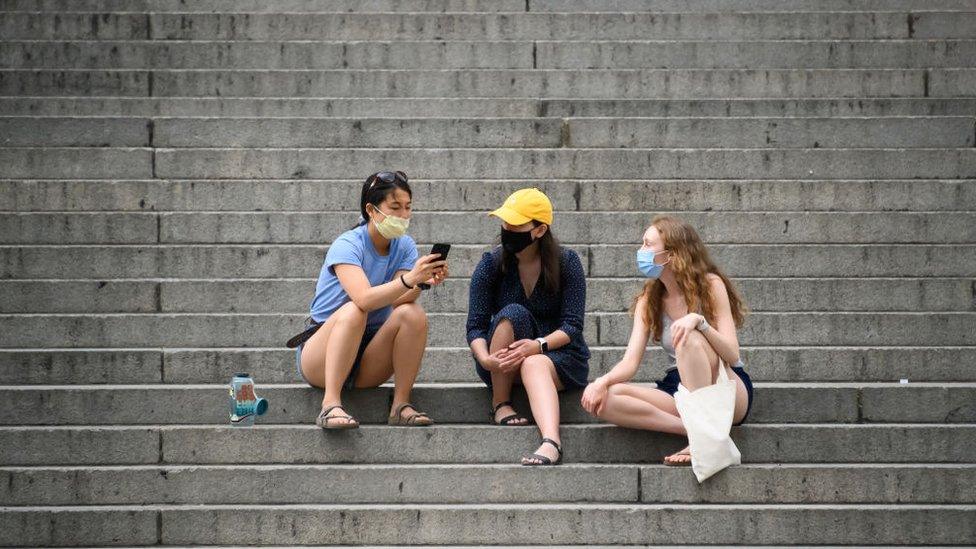 People wearing protective face masks sit on the steps of the Metropolitan Museum of Art during the coronavirus pandemic on May 30, 2020 in New York City