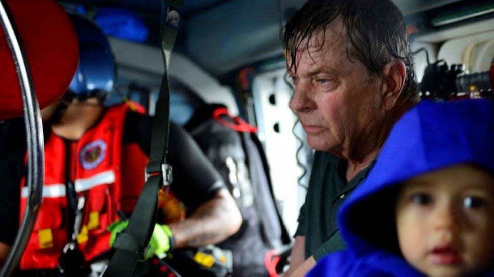 A man is pictured with a small child on board a rescue helicopter