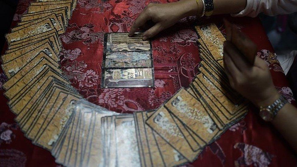 A fortune teller uses tarot cards to predict the future of a woman at a Buddhist temple in Bangkok