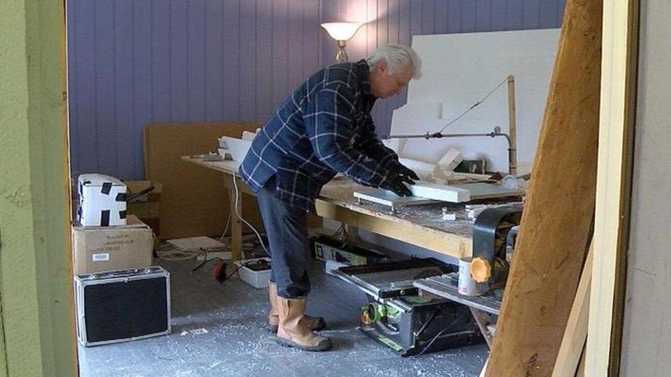 A man cutting polystyrene in his workshop.