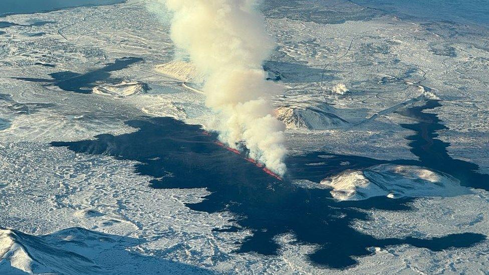 An aerial view of lava pouring from a volcanic fissure