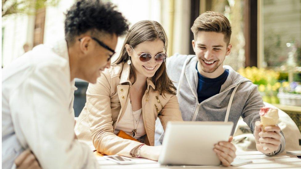 Three young people sitting around a laptop