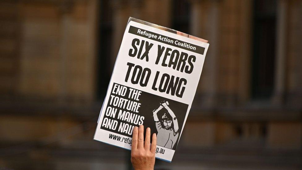 A demonstrator holds up a sign at a protest rally to demand humane treatment of asylum seekers.