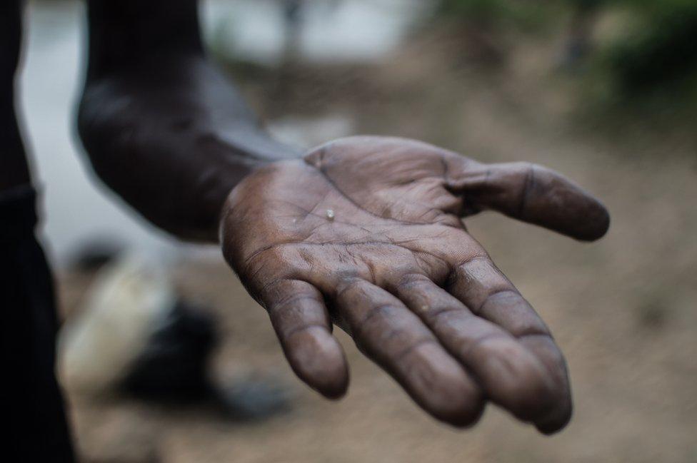 A man holds out a small diamond