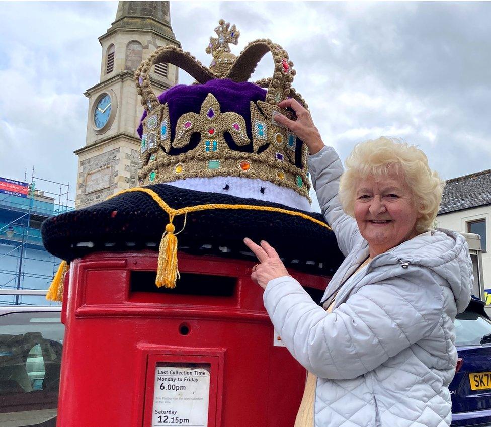 Daphne Pratt adjusts her giant crocheted crown on a postbox in Selkirk