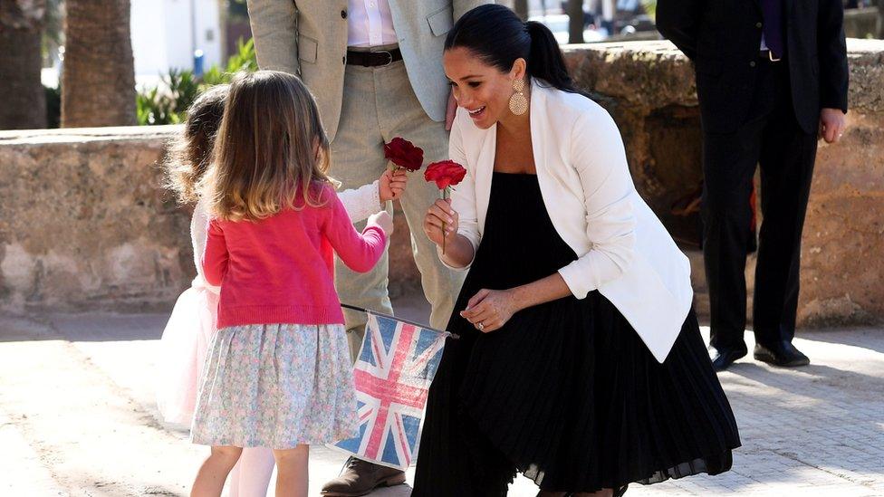 Duchess of Sussex is given flowers by two children during a visit to Morocco