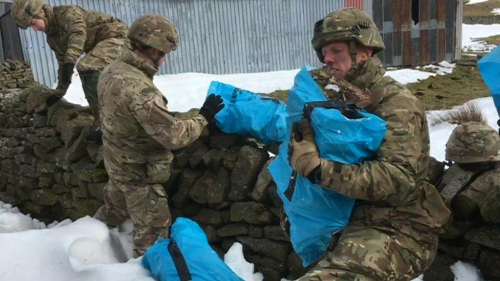 Supplies including logs are carried by Army soldiers at a drop-off near Kirkby Stephen