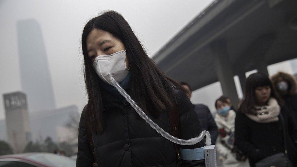 A woman wears a mask and filter as she walks during heavy pollution in Beijing, China