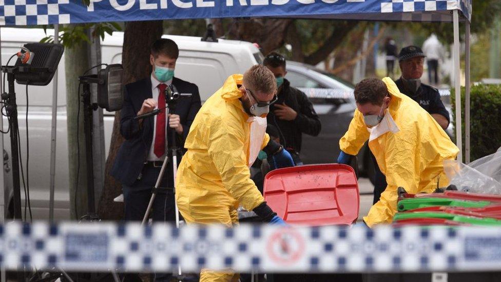 Police tipping out a bin as media film