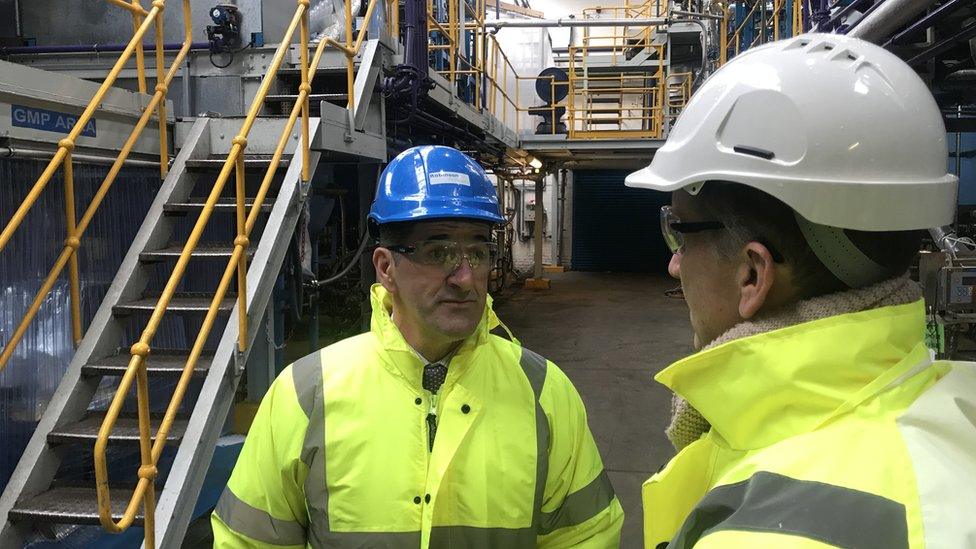 close up two men in hi vis and hard hats at factory talking