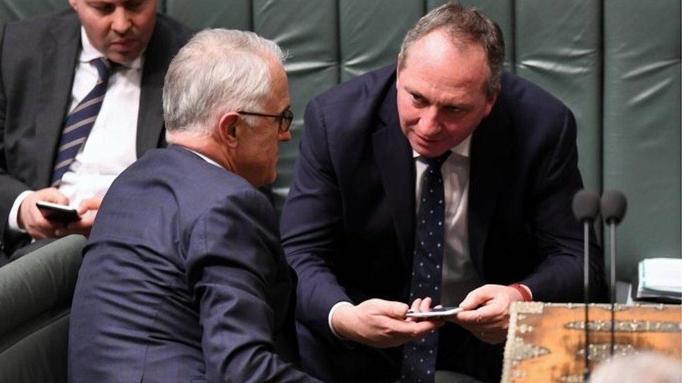 Australian PM Malcolm Turnbull (L) speaks to his deputy, Barnaby Joyce, in parliament