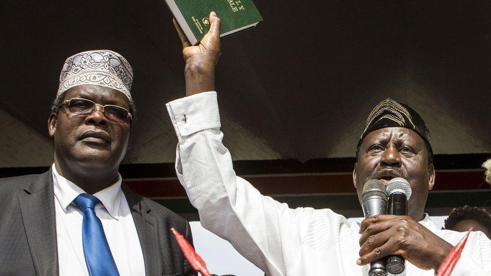 Kenya's opposition National Super Alliance (NASA) coalition leader Raila Odinga (2-L) holds up a bible as he swears-in himself as the 'people's president' on January 30, 2018 in Nairobi.