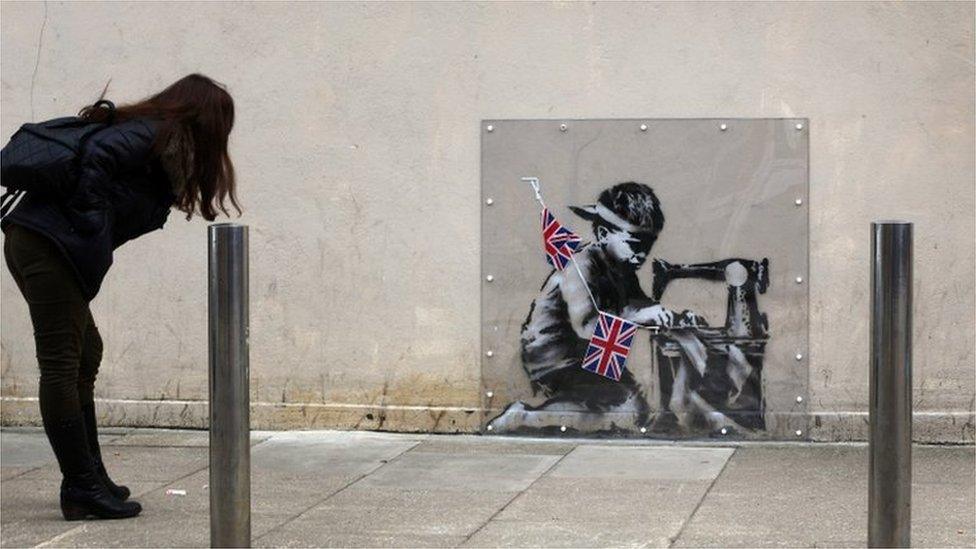 Woman looking at Banksy mural