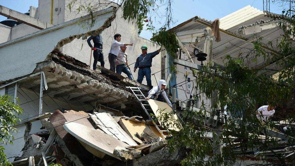 People stand at a building which collapsed after a quake rattled Mexico City