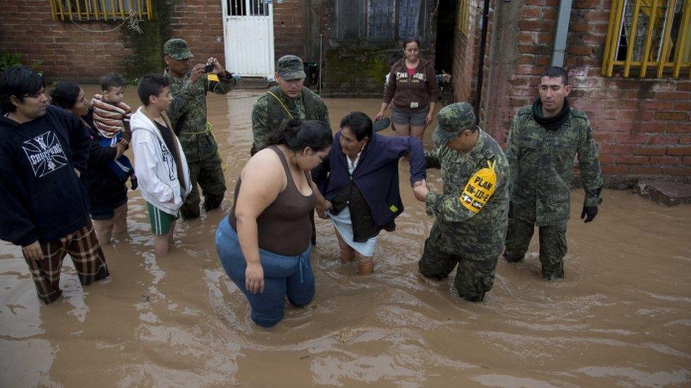 Rescuers help women near a flooded house in Mexico