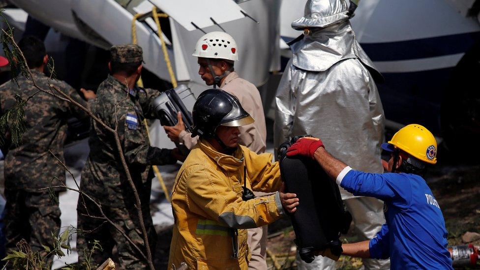 Rescue workers recover the luggage from the wreckage of a Gulfstream G200 aircraft that skidded off the runway