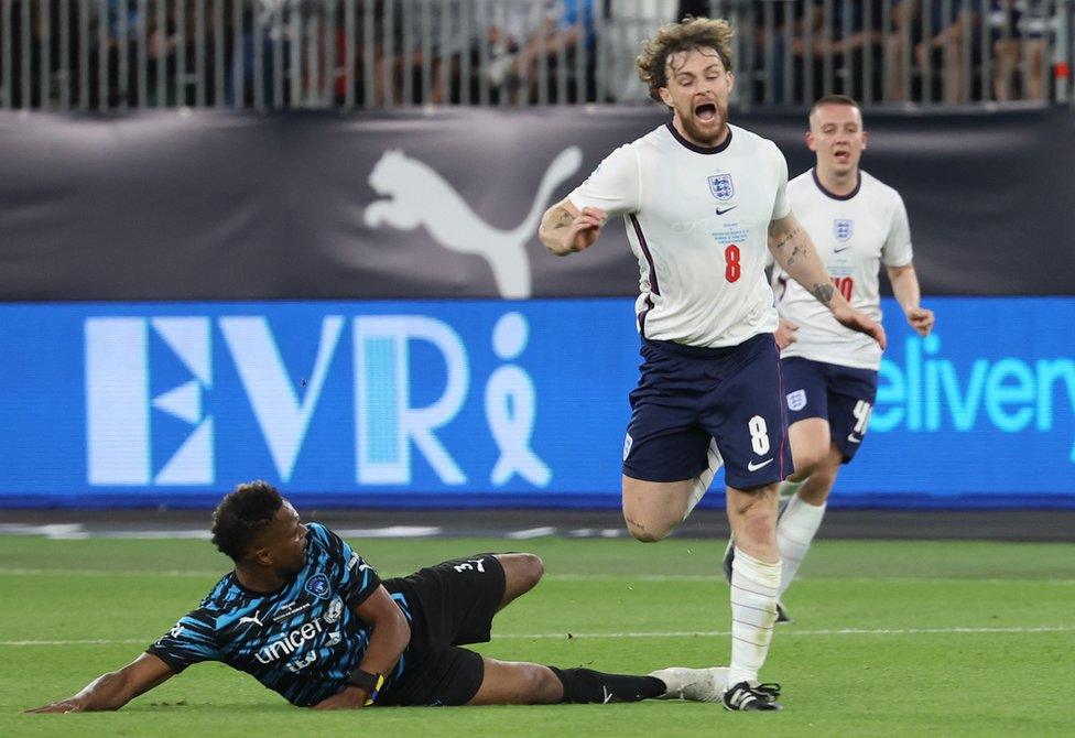 Tom Grennan receives a tackle from Patrice Evra