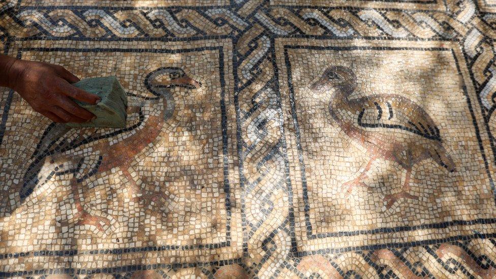 Salman al-Nabahin cleaning the mosaic floor discovered on his farm in Gaza