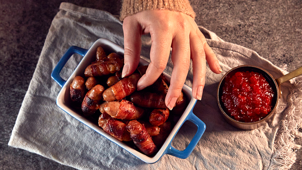 Woman reaching for pigs in blankets