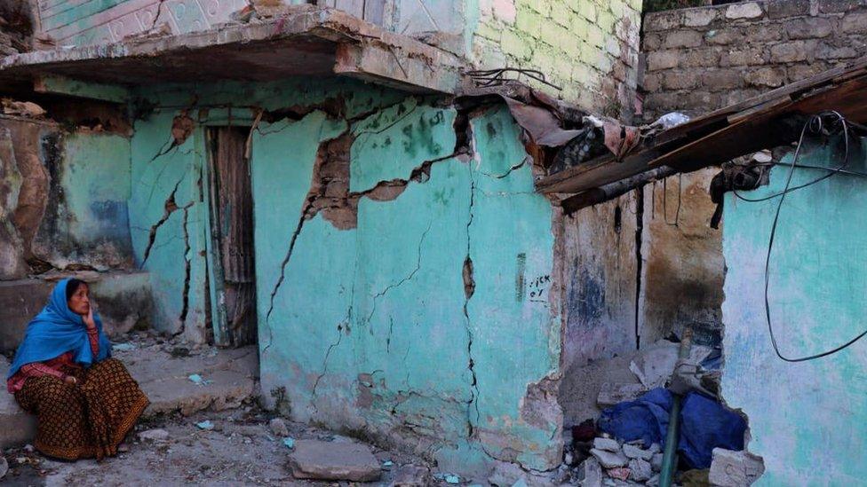 A resident sits next to a cracked wall of her house at Joshimath in Chamoli district of India's Uttarakhand state on January 8, 2023.