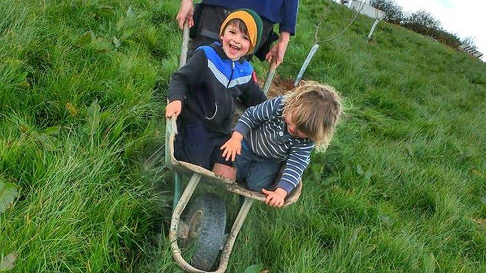 Two small boys in wheel barrow