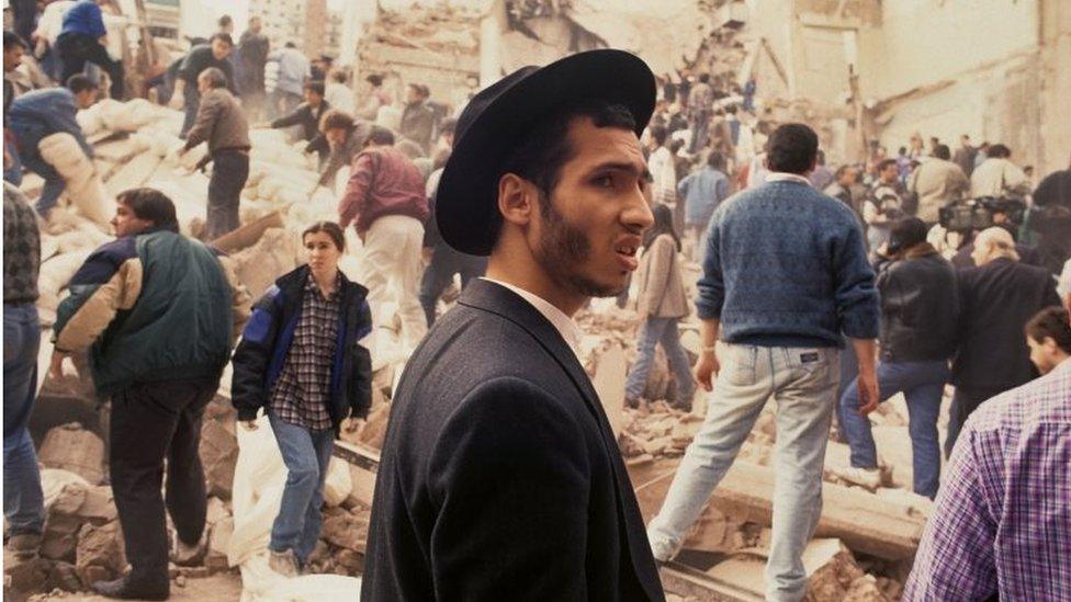 People look on after an explosives-laden truck blew up outside the Argentine Israeli Mutual Association (AMIA) building on July 18 1994, in Buenos Aires, Argentina.