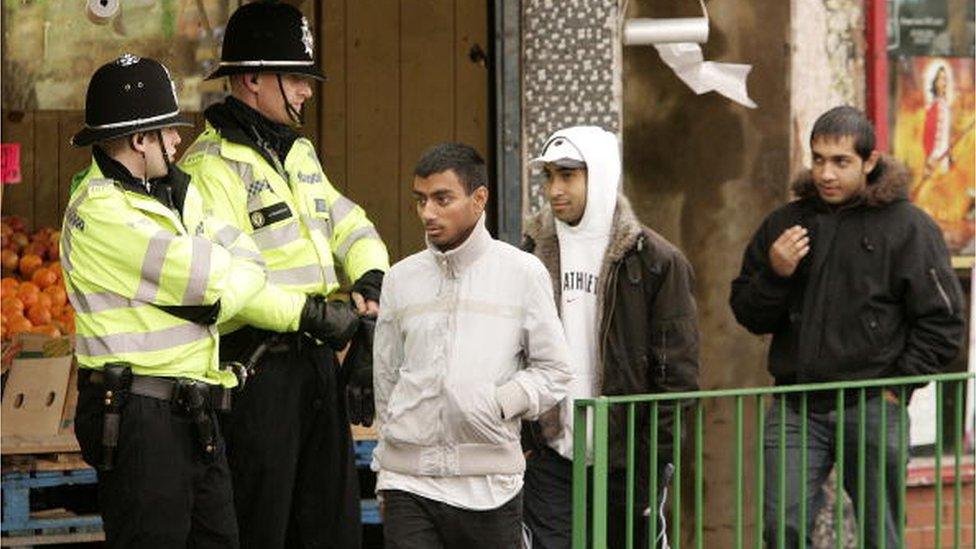 Local youths and police officers are seen in the Lozells Road area on October 23, 2005 in Birmingham, England.