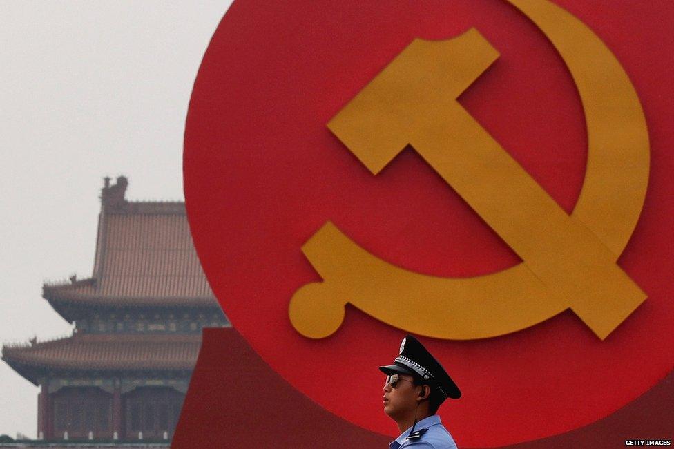 A policeman patrols under a giant communist emblem on the Tiananmen Square on 28 June 2011 in Beijing, China