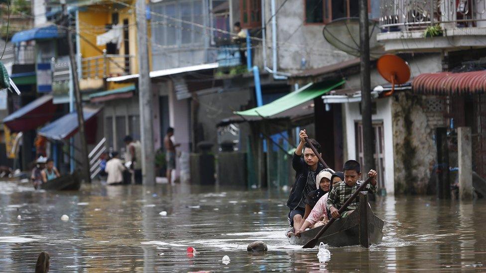 Group rowing a boat through a flooded street