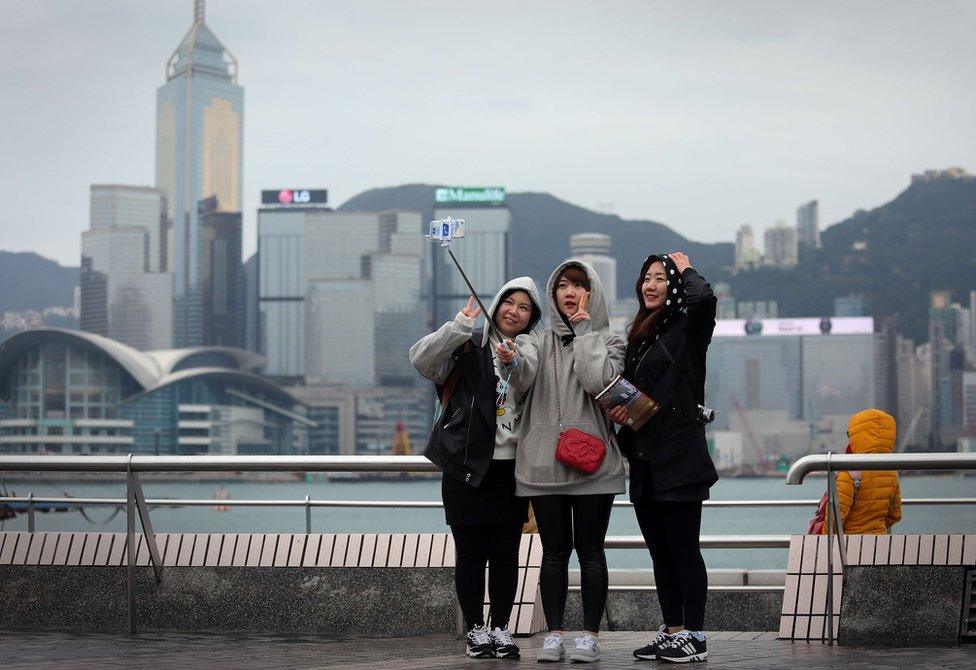 Three girls take a selfie as they brave the cold on a viewing deck next to Victoria Harbour in the Tsim Sha Tsui district of Hong Kong on 24 January 2016.