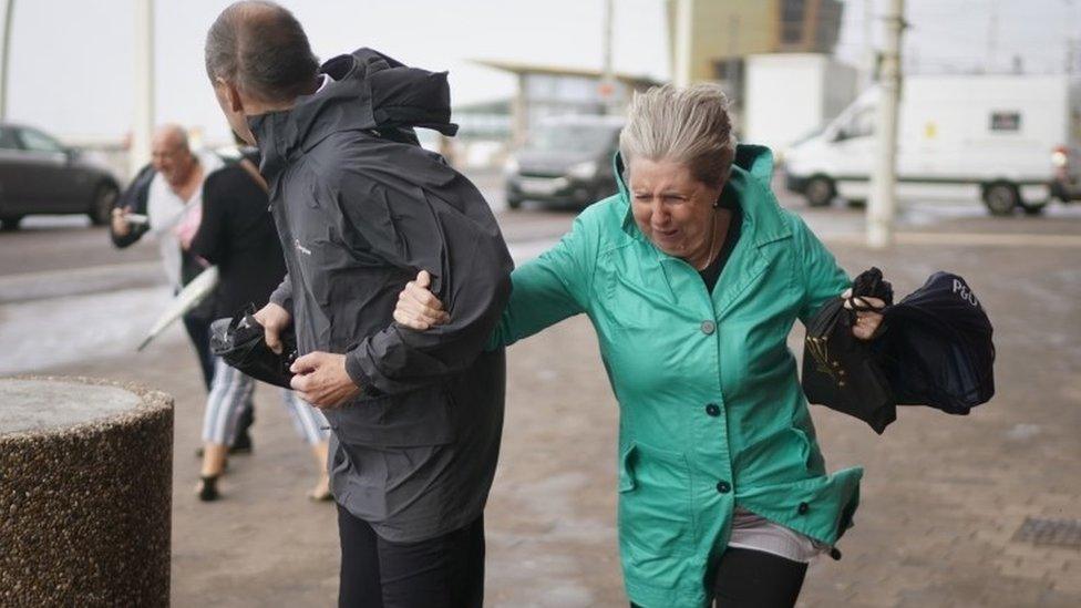 Members of the public struggle in the wind