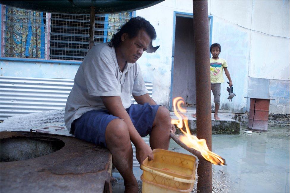 Picture of Kiribati man setting fire to a stick dipped in water