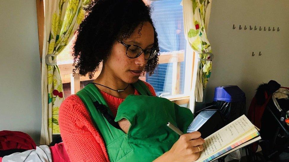 Woman writing with baby in sling