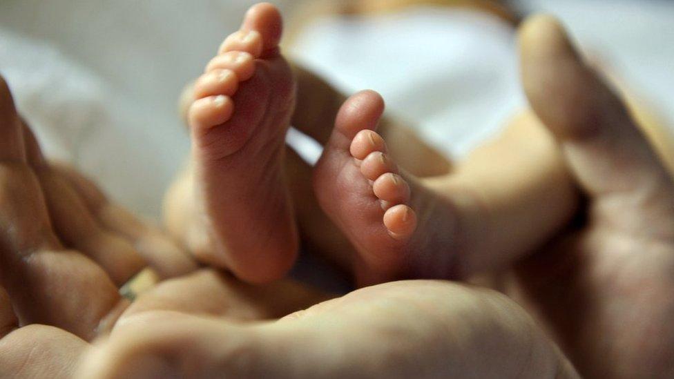 Baby's feet and parent's hands