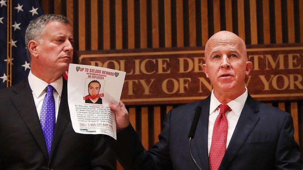 Mayor Bill de Blasio, holding a photo of Ahmad Khan Rahami, stands next to New York City's new police commissioner, James O'Neill