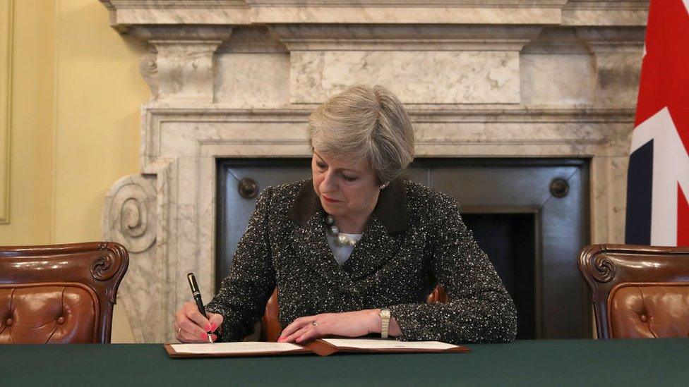 Theresa May writing at letter in downing street