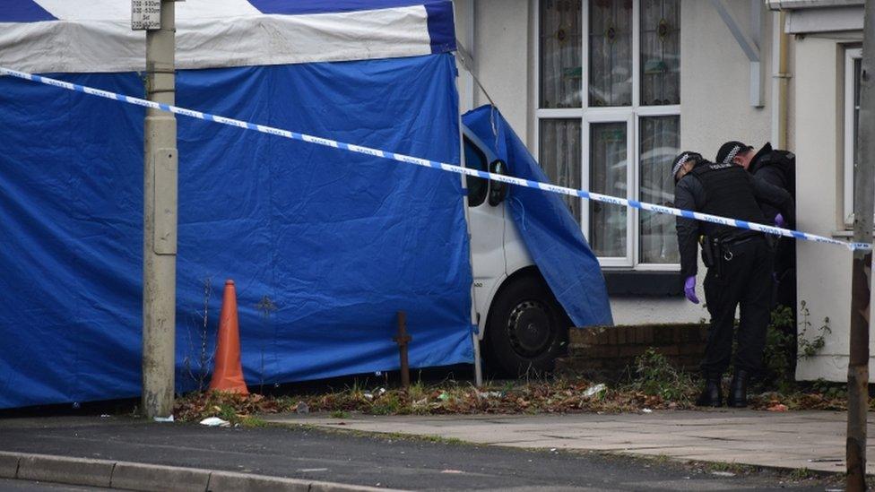 Police search the grounds of a nearby property after sealing off Queens Cross, Dudley, West Midlands,