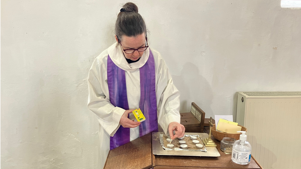 Rector Sharon Lord lighting a candle at All Saints' & St Margaret's Church in Pakefield in memory of Joy Middleditch