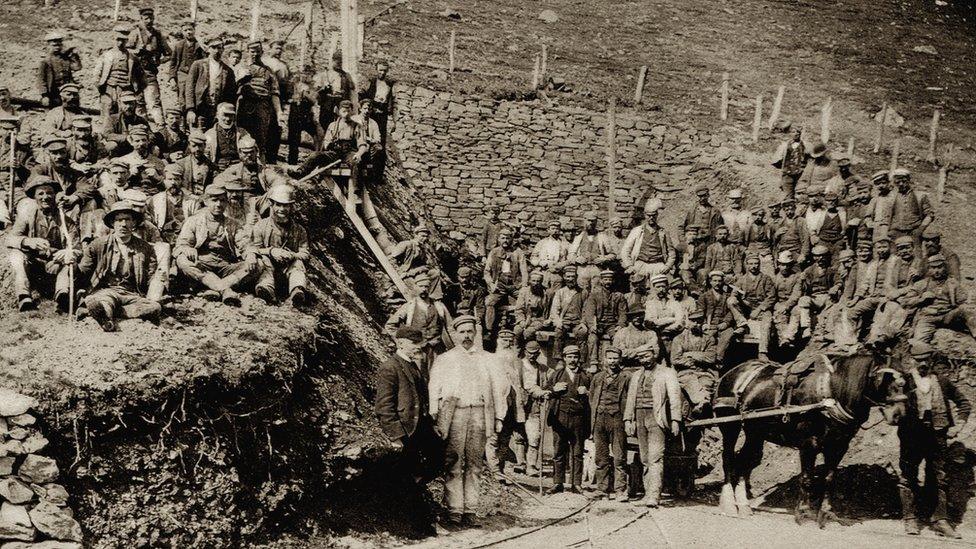 About 50 workers pose for an official photograph with a horse and cart also in view