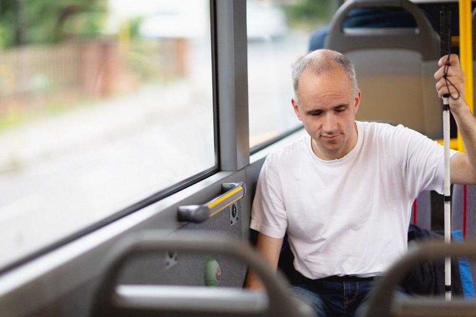 Man with white stick on bus