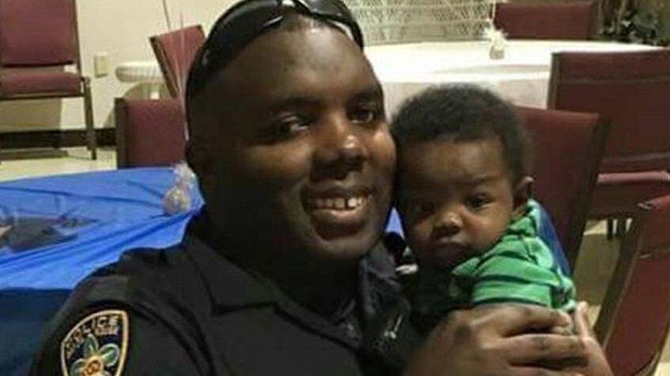 In this 2016 photo provided by Trenisha Jackson, her husband, Baton Rouge Police Officer Montrell Jackson, holds his son Mason at a Father's Day event for police officers in Baton Rouge