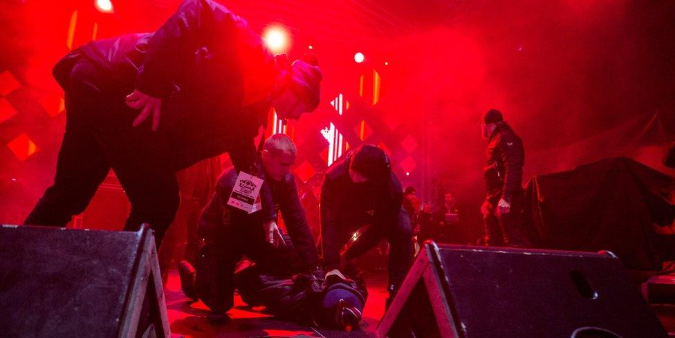 A man is held on the ground by security personnel after he attacked the mayor of Gdansk during a charity event in Gdansk on January 13, 2019