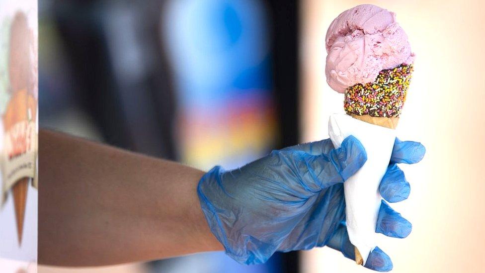 Close-up of an ice cream being sold, with a hand holding the cone