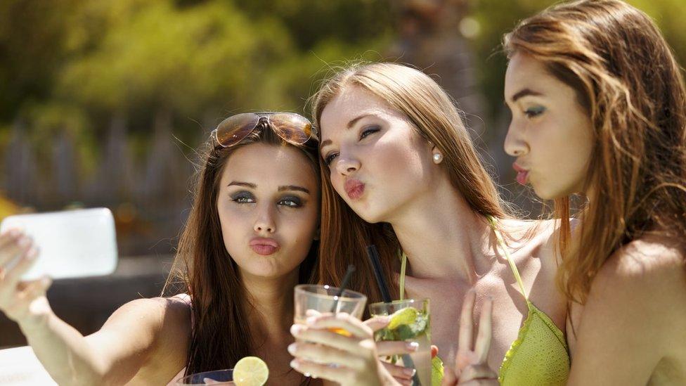 Women posing for a selfie by a poolside