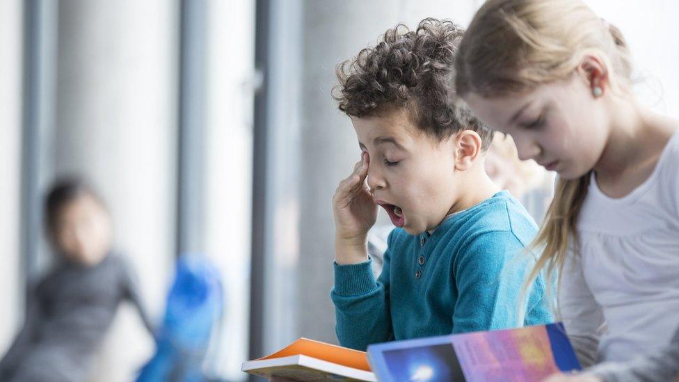two children reading - one is yawning
