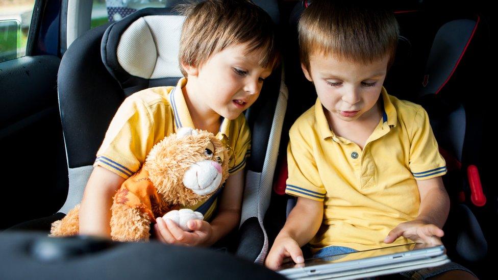 Children in car looking at iPad