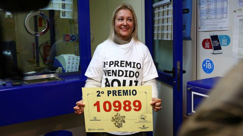 A worker of a lottery office in Madrid celebrates selling the number 10989 that got the second prize in the lottery draw in Madrid.