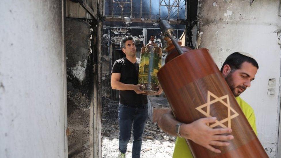 Men take out a Torah scroll from a burned synagogue in Lod, Israel (12 May 2021)