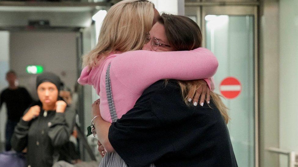 Women embrace as holidaymakers fleeing Greek wildfires arrive at Gatwick Airport