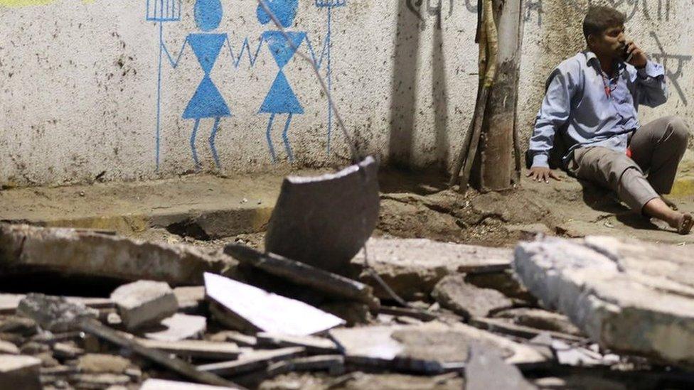 A man sits among the rubble